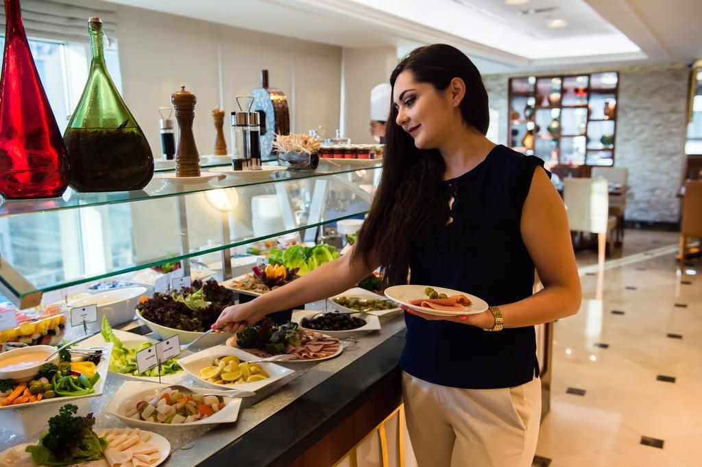 Grand Mercure Majlis Residences Abu Dhabi Exteriör bild A woman selecting food from a buffet